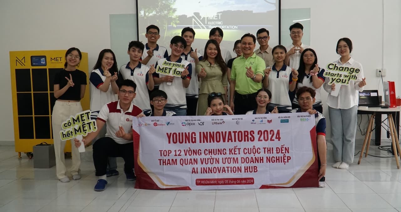 Group of participants posing in front of the hub with METRO banners and a yellow scooter
